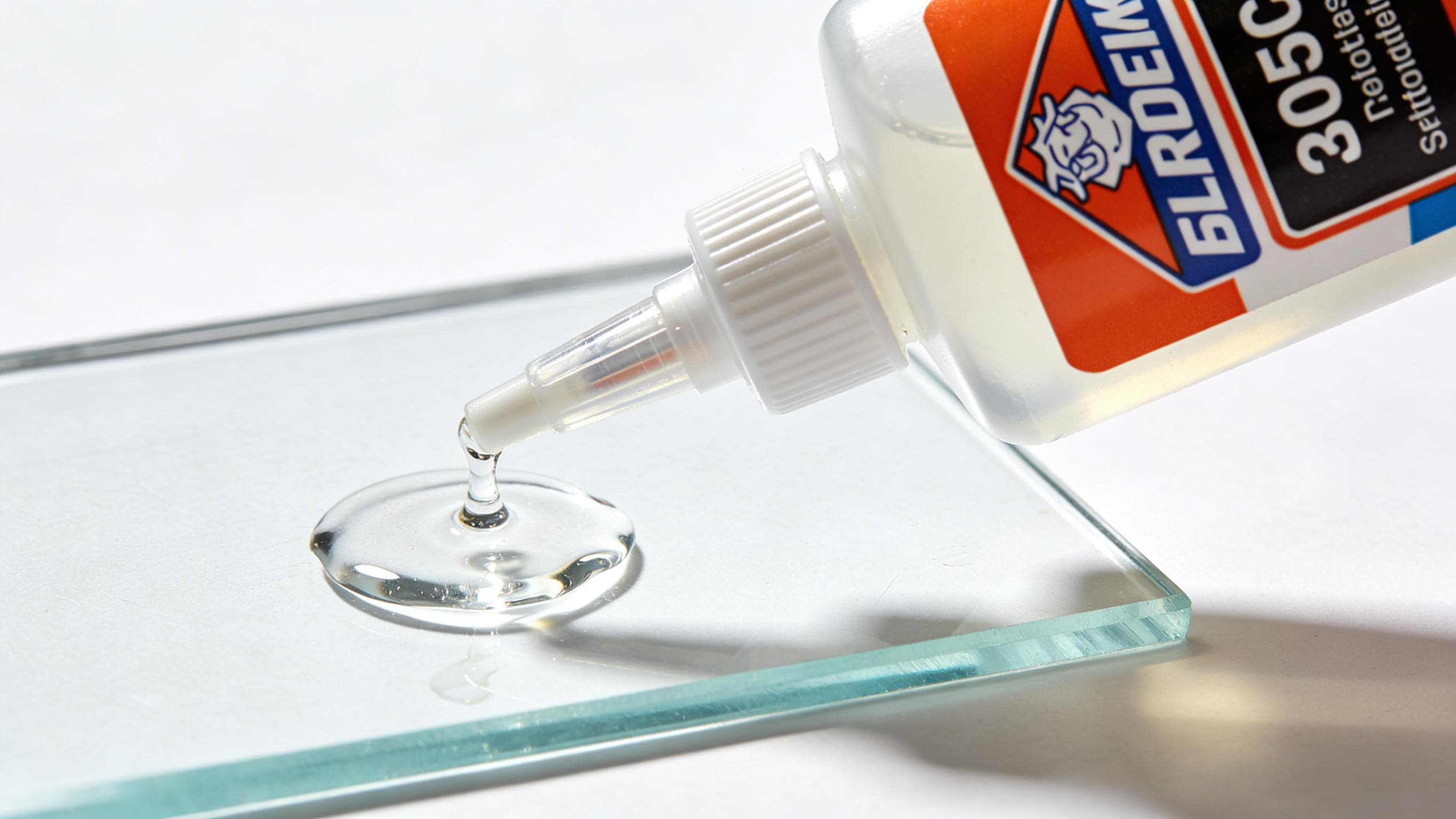 Clear glue dispensed from a bottle onto glass