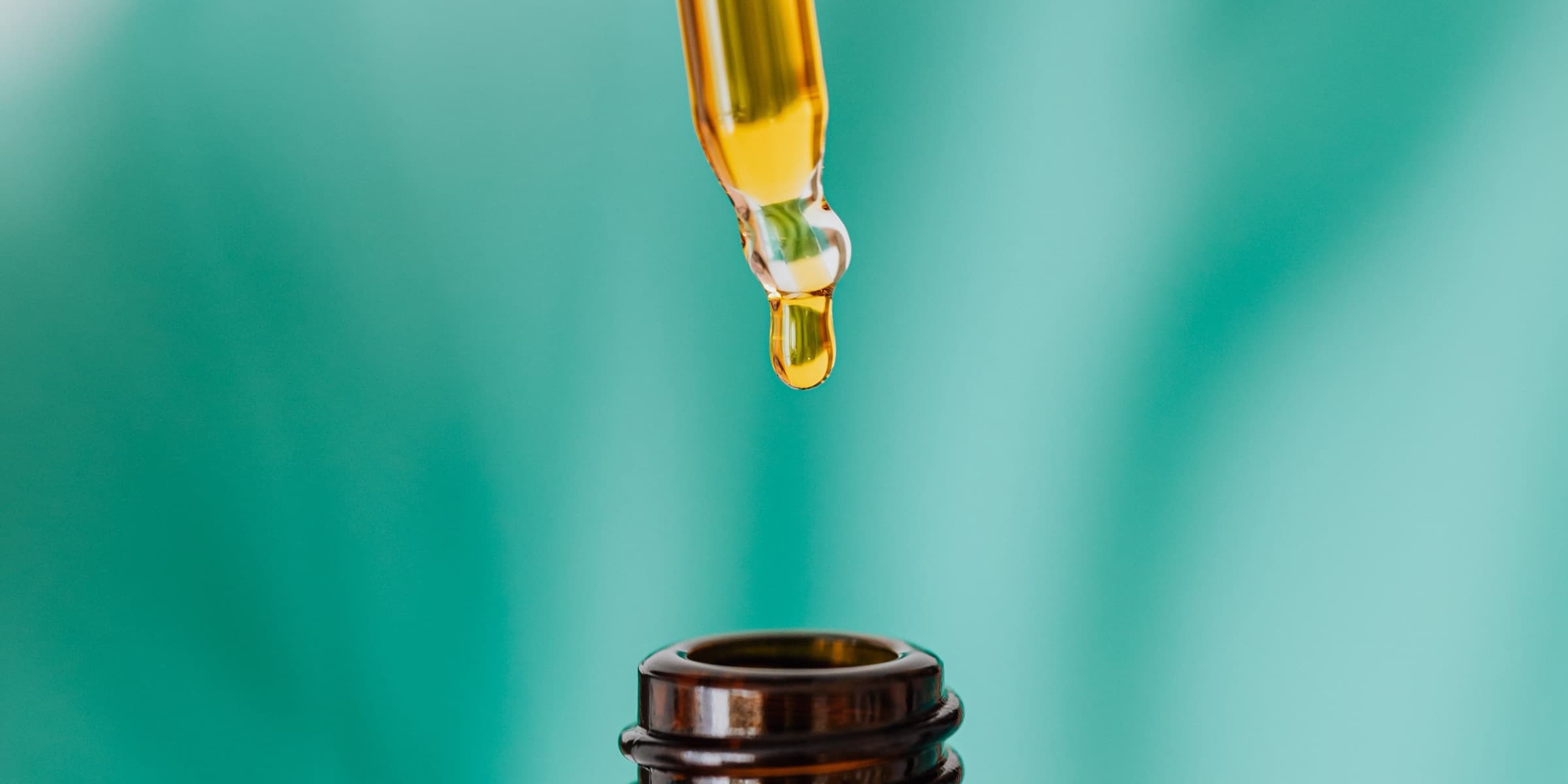 Dropper filling an amber bottle with oil